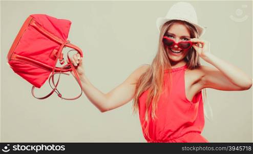 Cute attractive young woman girl in sunglasses, red shirt and straw hat with handbag in studio. Summer female fashion vogue.