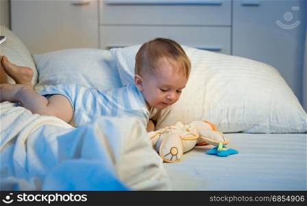 Cute baby boy crawling on bed at night