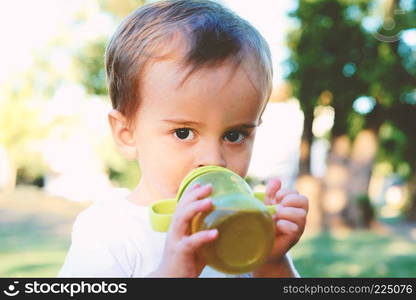 Cute Baby Boy Drinking Milk Bottle in a park