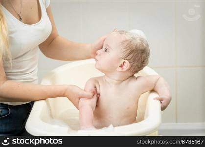Cute baby boy having bath and looking at mother