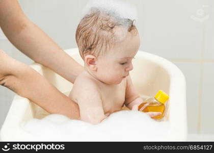 Cute baby boy having bath and playing with toys