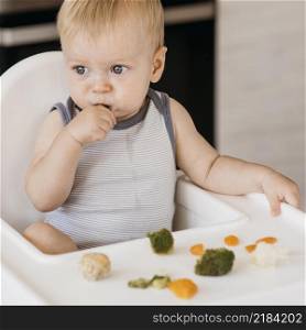 cute baby boy highchair eating vegetables
