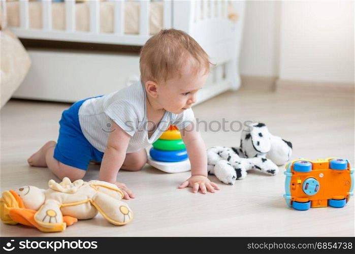 Cute baby boy playing with colorful toys on floor at living room