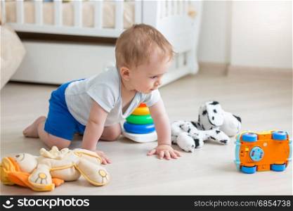 Cute baby boy playing with colorful toys on floor at living room