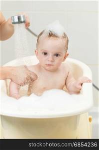 Cute baby boy sitting in bath full of foam
