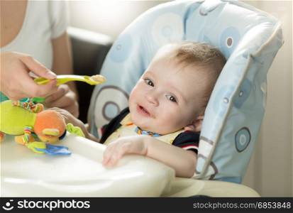 Cute baby boy sitting in highchair and looking at camera