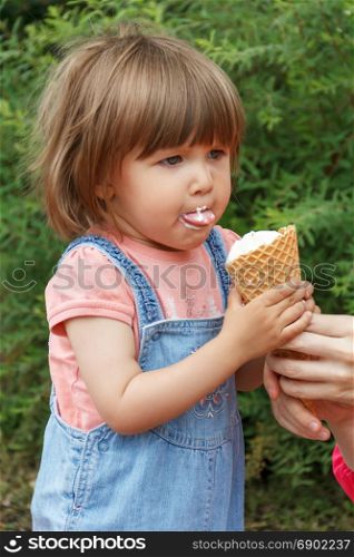 Cute baby girl are eating icecream in summer with put out tongue