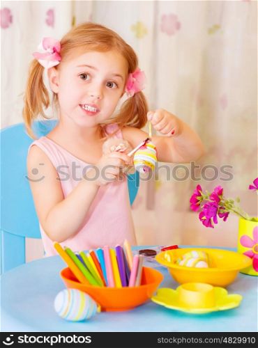 Cute baby girl decorated Easter eggs with colored paint at home, holiday celebration, spring season