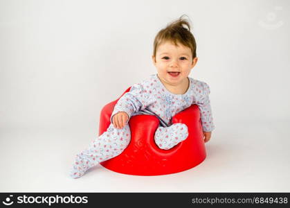 cute baby girl sitting in a sitter and making funny expressions