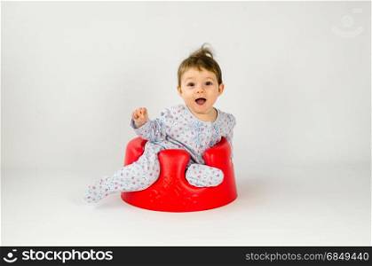 cute baby girl sitting in a sitter and making funny expressions