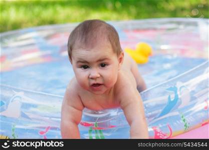 Cute baby in the inflatable pool on grass