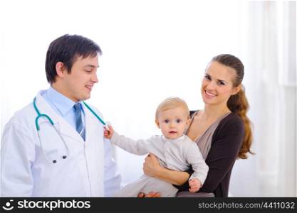 Cute baby on mothers hand touching stethoscope of pediatric doctor&#xA;