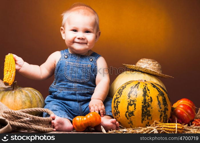 Cute baby posing on the background of pumpkins. Thanksgiving greetings. Postcard to the day of Thanksgiving