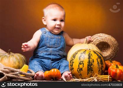 Cute baby posing on the background of pumpkins. Thanksgiving greetings. Postcard to the day of Thanksgiving