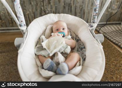 cute baby with pacifier lying baby carriage home