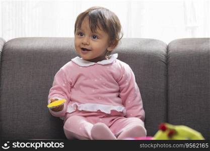 Cute baby with toy in hand looking away