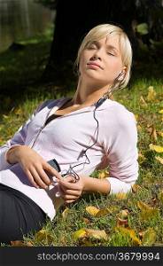 cute blond girl enjoying the sun and listening music with mp3
