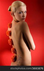 cute blond girl on red background with some red flowers on her back looking in camera