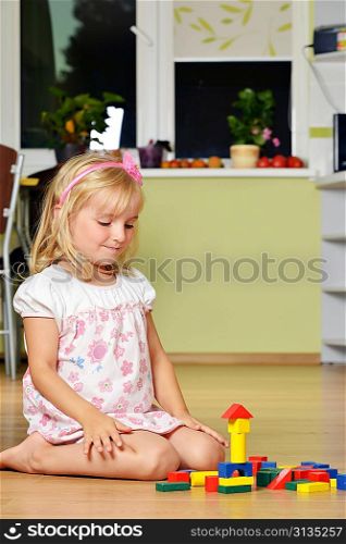 cute blond girl playing with cubes at home