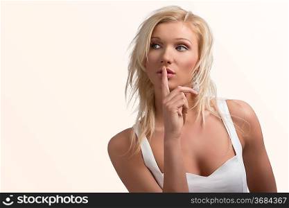 cute blond sexy girl in white dress, she looks at right with index finger on the mouth
