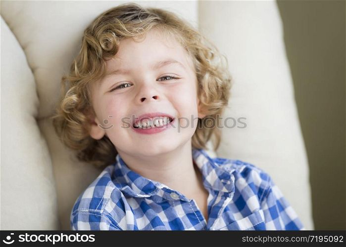 Cute Blonde Boy Smiling for Portrait Sitting in Chair.