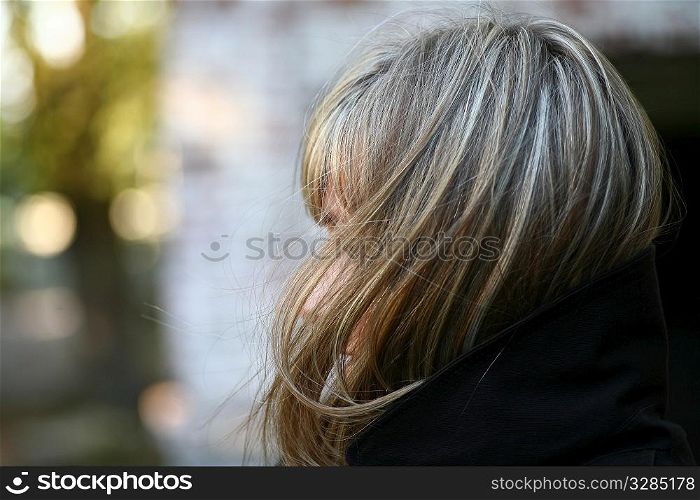 cute blonde girl in profile against outdoor background