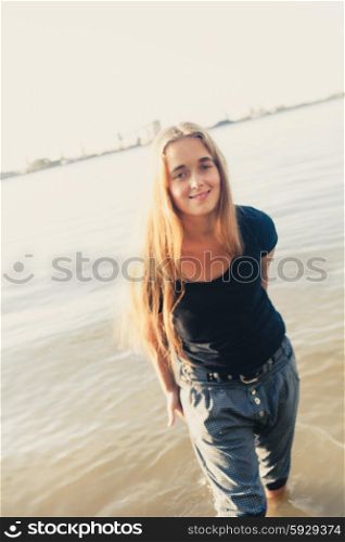 Cute blonde smiling against water of lake.