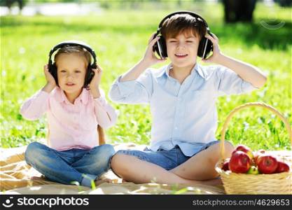 Cute boy and girl in summer park listening to music. Summer weekend