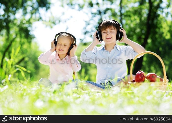 Cute boy and girl in summer park listening to music. Summer weekend