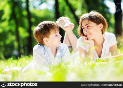 Cute boy and young woman in summer park. Weekend in park