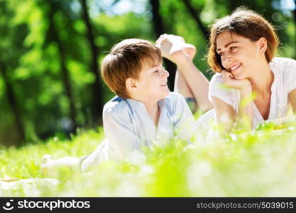 Cute boy and young woman in summer park. Weekend in park