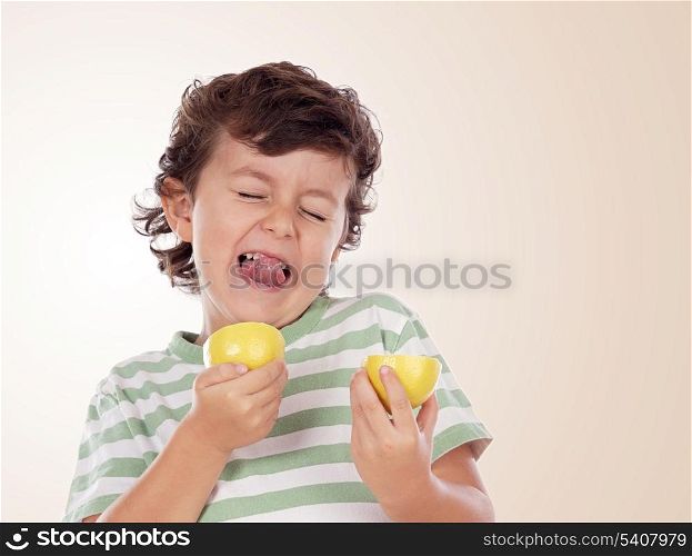 Cute boy eating lemon isolated on a orange background