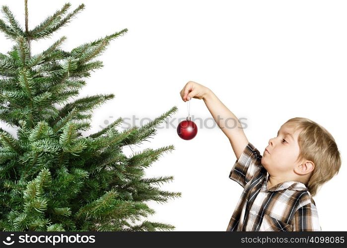 Cute boy hanging the first Christmas decoration on the tree.