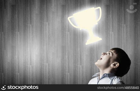 Cute boy of school age looking up at cup