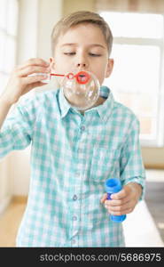 Cute boy playing with bubble wand at home