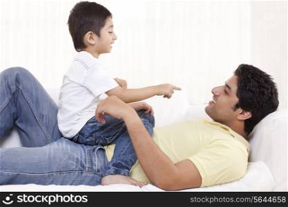 Cute boy sitting on father at home
