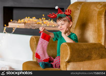 Cute boy waiting for a gift from Santa Claus, near the Christmas tree. Happy childhood, time to make wishes come true. Merry Christmas.. Cute boy waiting for a gift from Santa Claus, near the Christmas tree. Happy childhood, time to make wishes come true.