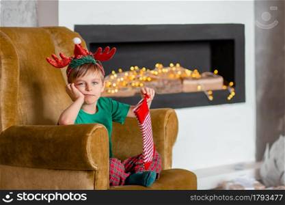 Cute boy waiting for a gift from Santa Claus, near the Christmas tree. Happy childhood, time to make wishes come true. Merry Christmas.. Cute boy waiting for a gift from Santa Claus, near the Christmas tree. Happy childhood, time to make wishes come true.