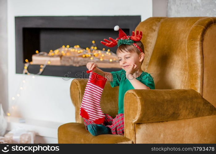 Cute boy waiting for a gift from Santa Claus, near the Christmas tree. Happy childhood, time to make wishes come true. Merry Christmas.. Cute boy waiting for a gift from Santa Claus, near the Christmas tree. Happy childhood, time to make wishes come true.