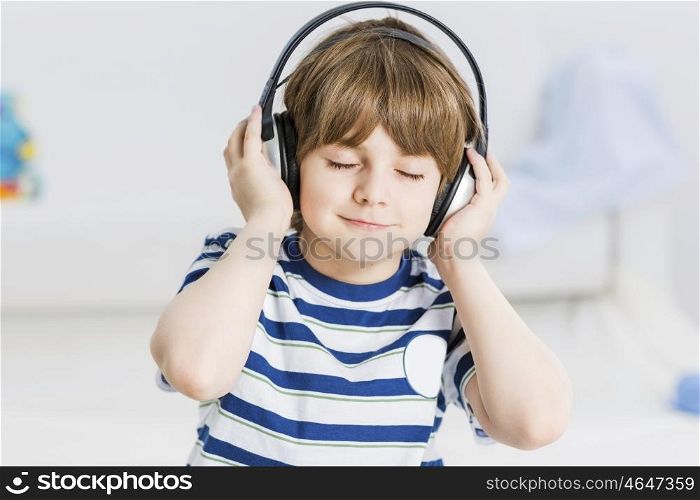 Cute boy wearing headphones and enjoying music. I like this song