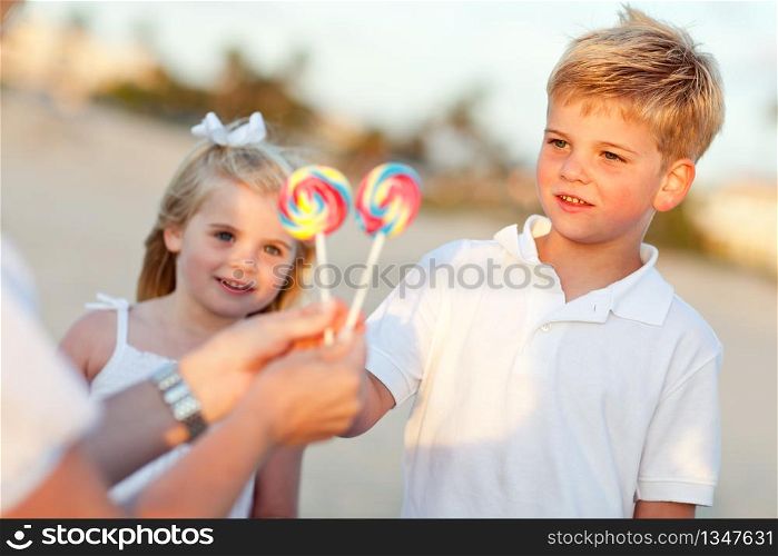 Cute Brother and Sister Picking out Lollipop from Their Mom at the Beach.