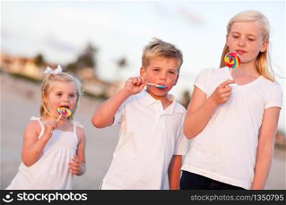 Cute Brother and Sisters Enjoying Their Lollipops at the Beach.
