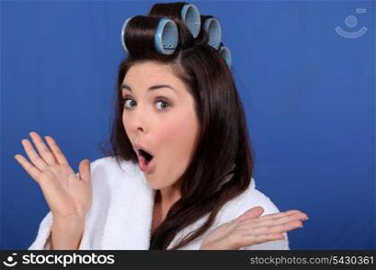 cute brunette in bathrobe with hair curlers against blue background