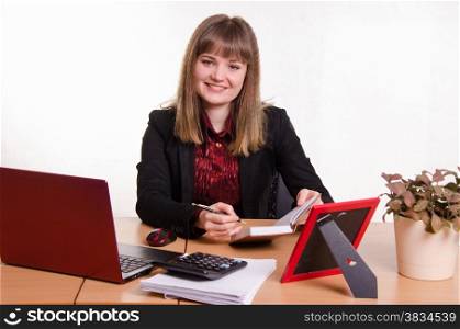 Cute business woman in the office at the computer. Joyful Girl sitting at office table