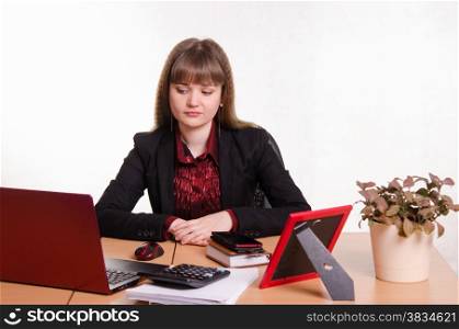 Cute business woman in the office at the computer. Sad girl sits at office table