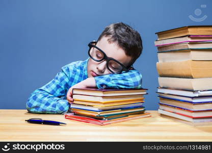 Cute child asleep at the desk in school library. Pupil in glasses against many books. Cute child asleep at the desk in school library