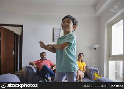 Cute child looking away with smile and the rest of his family sitting on sofa away