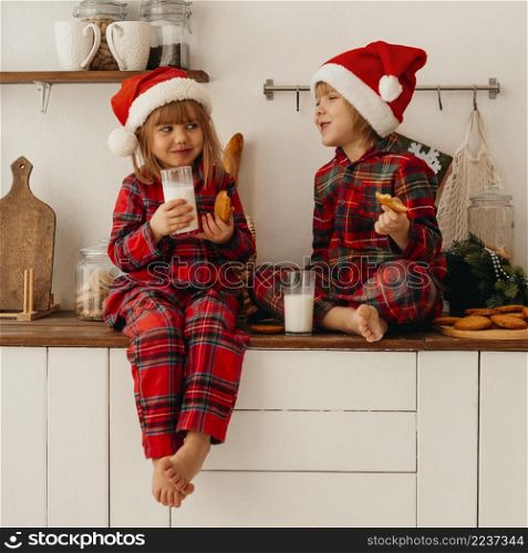 cute children eating christmas cookies drinking milk