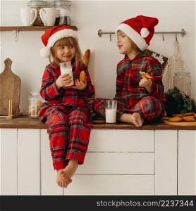 cute children eating christmas cookies drinking milk