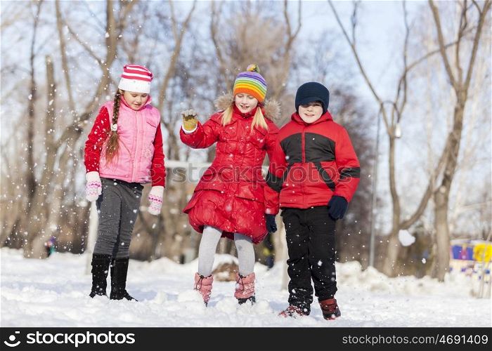 Cute children jumping and having fun in winter park. Winter activities